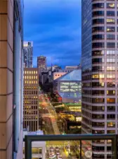 From this height the rhythm of the city reveals itself in illuminated towers and streets unfolding toward the waterfront.