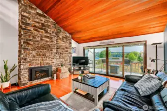 The beautiful propane fireplace has a floor to ceiling stone wall that meets the vaulted wood ceiling.