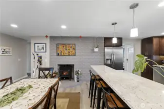 Eat-in kitchen with breakfast bar seating for stools and a cozy fireplace as the focal point.