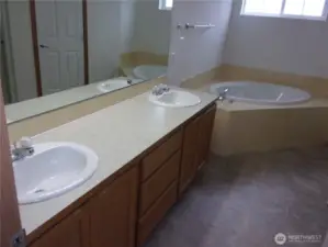 Primary bath has double sinks, tiled soaking tub, and separate shower.