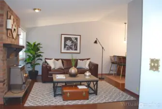 This is an virtually staged view in to the living room with hand scraped style wood flooring and a wood burning stove to provide peace of mind in emergencies.  This home blends functionality with location—what an opportunity!