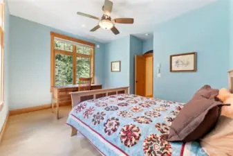 Main floor bedroom with lovely natural light, peaceful garden views, and private access to the adjacent full bath.