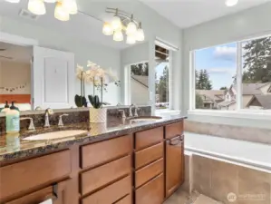 Granite countertops, tile flooring and large tub in the primary bathroom.