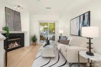 Open living room featuring hardwood floors, gas fireplace, and sliding door to private balcony.