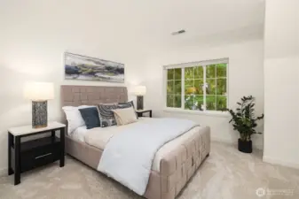 Spacious primary bedroom with wall-to-wall carpet, large window, and peaceful treetop views.