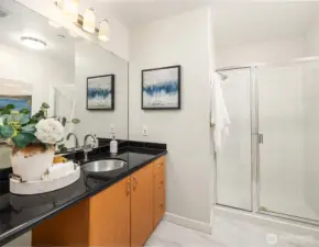 Primary bathroom with extended vanity, solid surface countertops, and walk-in shower with glass doors.