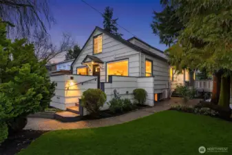 Looking NW from front lawn to front deck and house. Note extra entrance to kitchen from the side. Note heat pump for A/C and heat.