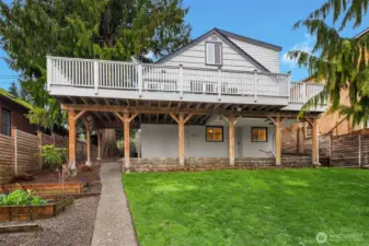 Looking west from the backyard to house. Note garden area to the left. Patio under Main level deck with entrance to Lower Level.