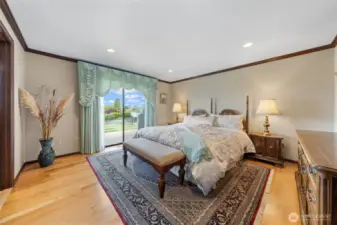 The primary suite on the main level features a spacious walk-in tile shower, dual sinks, granite countertops, a custom-designed closet, sophisticated wood cabinetry, and a large window that fills the space with ample light.