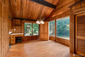 The dining room plays peek-a-boo with the outdoors—windows catching swaths of green and even a glimpse of the fairy-tale shed beyond. A hutch settles happily into the corner, a built-in desk moonlights as a coffee bar, and to the left, the kitchen leans in to join the conversation.
