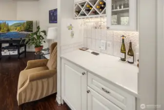 The wet bar area in the Family Room with mini fridge, wine bottle holder, and custom cabinetry