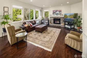 Family Room with newer flooring, gas fireplace w/ stone mantle, and views out into the backyard, and custom blinds