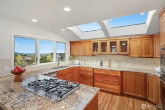 Well-maintained chef’s kitchen with skylights — bright, airy workspace, gleaming surfaces, and pristine appliances.