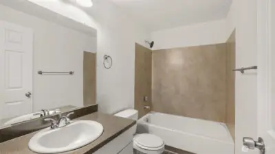 Centrally located full bath with sleek countertops and white shaker cabinetry.