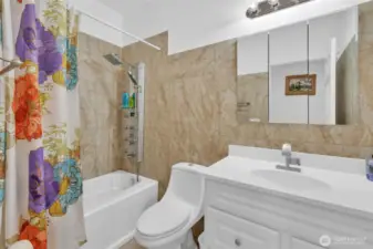 Guest bath has tile floor and tile tub surround. The spa like shower fixture mimics the one in the primary walk in shower. So many settings to chose from for that perfect mix of relaxing spray.