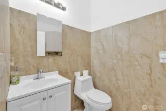 The half bath is just off the main living space. It also has tile floors and tile surrounding the space.