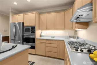 This kitchen includes gas cooking and ample counters and cabinetry with under cabinet lighting. There is also a pantry closet next to the utility room to the left of this photo.