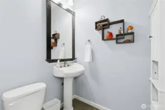 Powder Room:  Crisp, clean, and thoughtfully designed, this main-level powder room offers timeless simplicity with its pedestal sink, soft color palette, and elegant framed mirror. A perfect blend of practicality and charm for guests and everyday use.