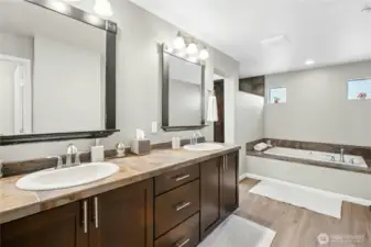 Primary Bathroom:  A touch of everyday luxury — the primary bath offers a deep soaking tub, dual vanities, and warm, natural finishes. Soft light filters through high windows, creating a relaxing and private atmosphere perfect for unwinding at the end of the day.