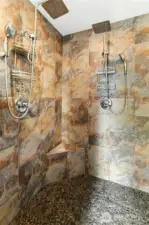 Walk-In Shower:  A spa retreat right at home — the beautifully tiled walk-in shower features dual rainfall heads, natural stone pebble flooring, and a built-in bench for ultimate comfort. Earth-toned tile creates warmth and texture, making this space both functional and indulgent.