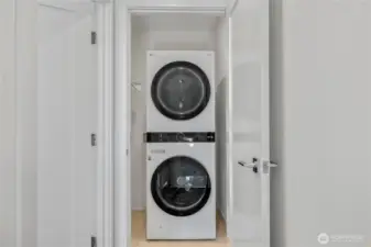 Washer and dryer closet on the upper level, conveniently located off the primary bedroom, with space for hanging clothing.