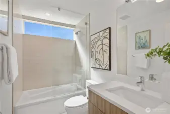 Modern full guest bathroom on the lower level featuring a glass-enclosed shower in place of a shower curtain.
