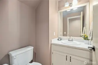 Main floor half bath with updated lighting, neutral tones, and classic white vanity—convenient for guests.