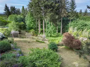 The yard bursts with flowering trees, climbing vines, and rhododendrons—just waiting for your care and vision to restore it to the garden showcase it once was.