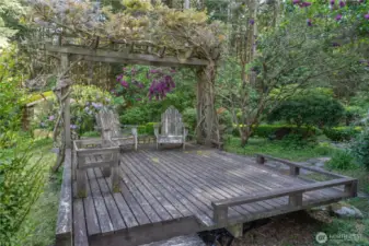 Relax beneath a vine-draped arbor on this charming wood deck—an inviting canvas ready for your personal touch. With a little love, it transforms into a storybook retreat, perfect for morning coffee or evening wine.