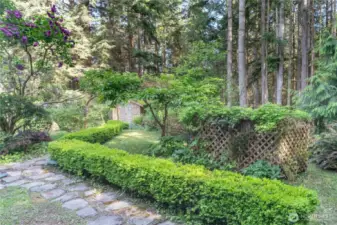 Stone walkways, flowering trees, soaring firs and cedars all add to the beauty of this property. The propane tank is behind the lattice fence on the right.