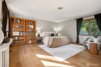 The spacious primary suite feels like a retreat in the treetops, with soft natural light filtering through the windows. Its generous layout easily accommodates a king bed and comfortable sitting area. The built in bookcase even offers a bit of a surprise!