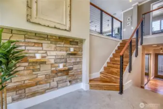 The entry way has a modern flare with concrete floors and a unique stone wall.