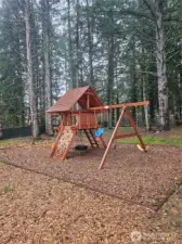 Swing set with slide and climbing area.