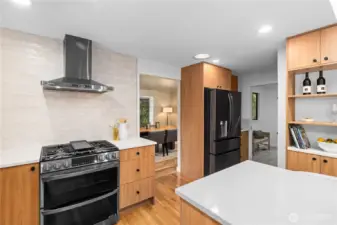 Gas range with vent hood and tile backsplash, positioned for ease of cooking and connection to adjacent spaces.
