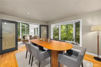 Formal dining room surrounded by windows and natural greenery, creating a warm and inviting setting for gatherings both large and small.