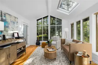 Sunroom with vaulted ceilings, skylight, and walls of glass offers a flexible space for relaxing, working, or simply enjoying the peaceful setting.