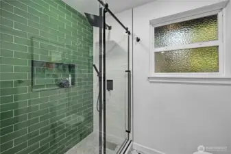 Designer tile, matte black fixtures, and a walk-in shower with built-in niche create a bold, modern bathroom statement.