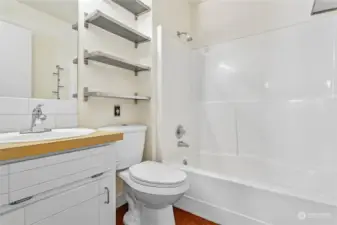 Full bathroom with newer toilet and lots of shelving and storage