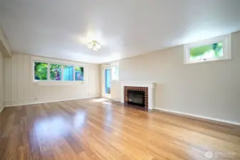 Lower level Family Room, with a cozy wood burning fireplace. The door leads to the south side of the home, as well as another private patio that faces Lake WA.