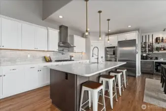 View of kitchen with quartz countertops and island with seating for four.