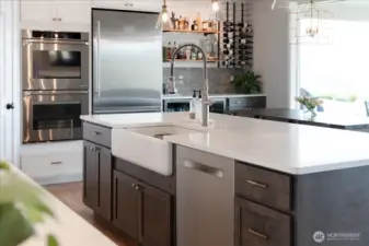 Kitchen with quartz countertops, farmhouse sink, stainless steel appliances and built in bar.