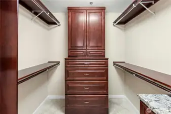 This remodeled walk-in closet in the primary suite has plenty of hanging space plus built-in cherry dressers to match the bath vanity.