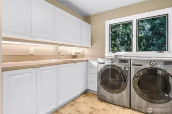 Featuring generous counter space and custom cabinets with drawers, this well-designed laundry room offers both functionality and convenience for all your storage needs.