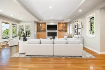 Rich hardwood floors and a stately gas fireplace with a stone surround anchor the space, while custom natural wood shelving adds both function and refined artistry.