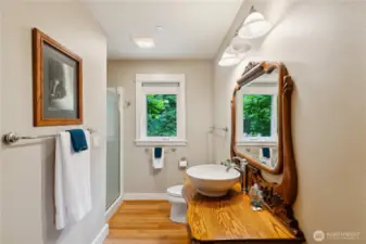 The 3/4 bathroom in the main level hallway has a solid oak custom vanity.