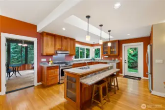 Granite breakfast bar in the kitchen is attached to the butcher block island, with prep sink. Glass display cabinets.