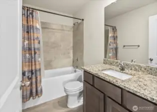 Full guest bath with tub and tiled shower and granite topped vanity.