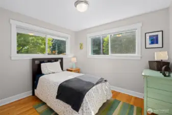Sunny corner bedroom with hardwood floors and garden views