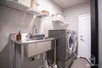 Laundry room with large sing and access to the garage beyond.  Washer and dryer stay