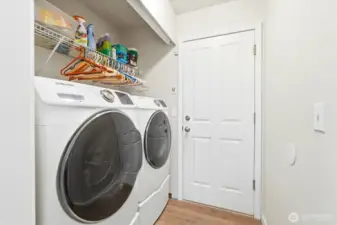 Well-organized laundry space with shelving for everyday essentials and garage access through the doorway.